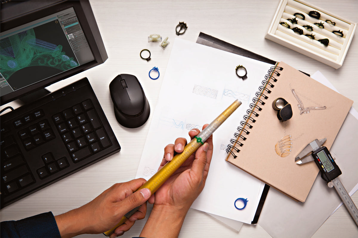 Person holding a stylus over a desk with a tablet, keyboard, and various items.