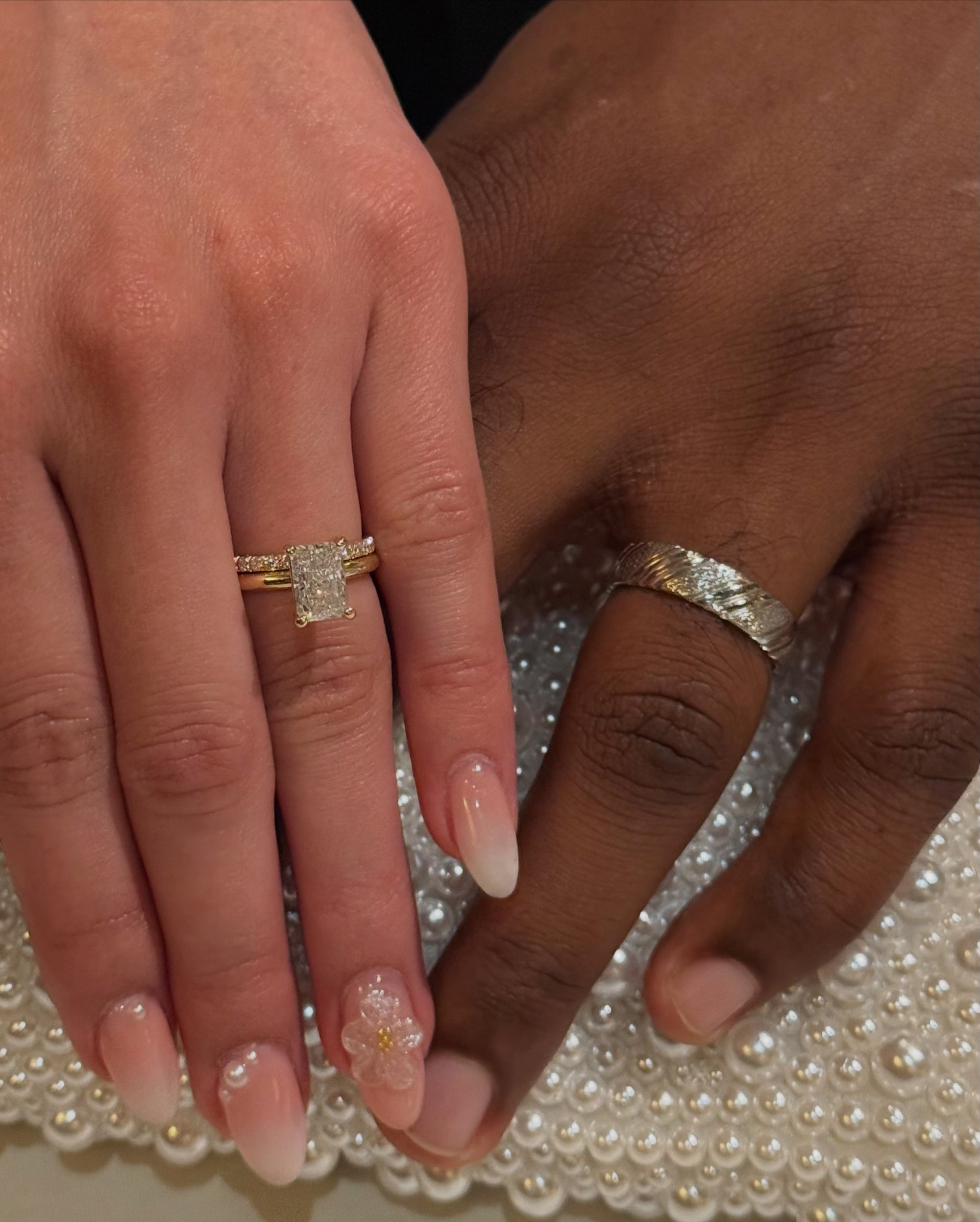 Two hands with gold rings on a textured surface