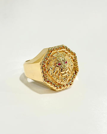 Gold ring with intricate design on a light beige background