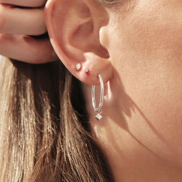 Close-up of an ear wearing two earrings with a blurred background
