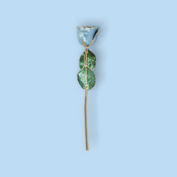 Decorative hair stick with green leaves and a blue stone on a light blue background