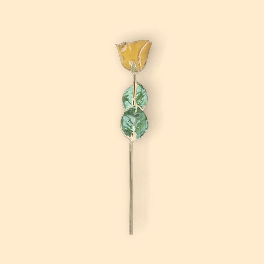 Decorative hairpin with gold top and green leaves on a beige background
