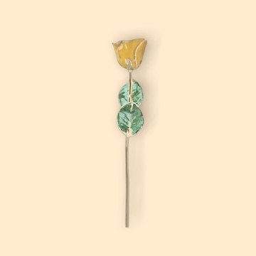 Decorative hairpin with gold top and green leaves on a beige background