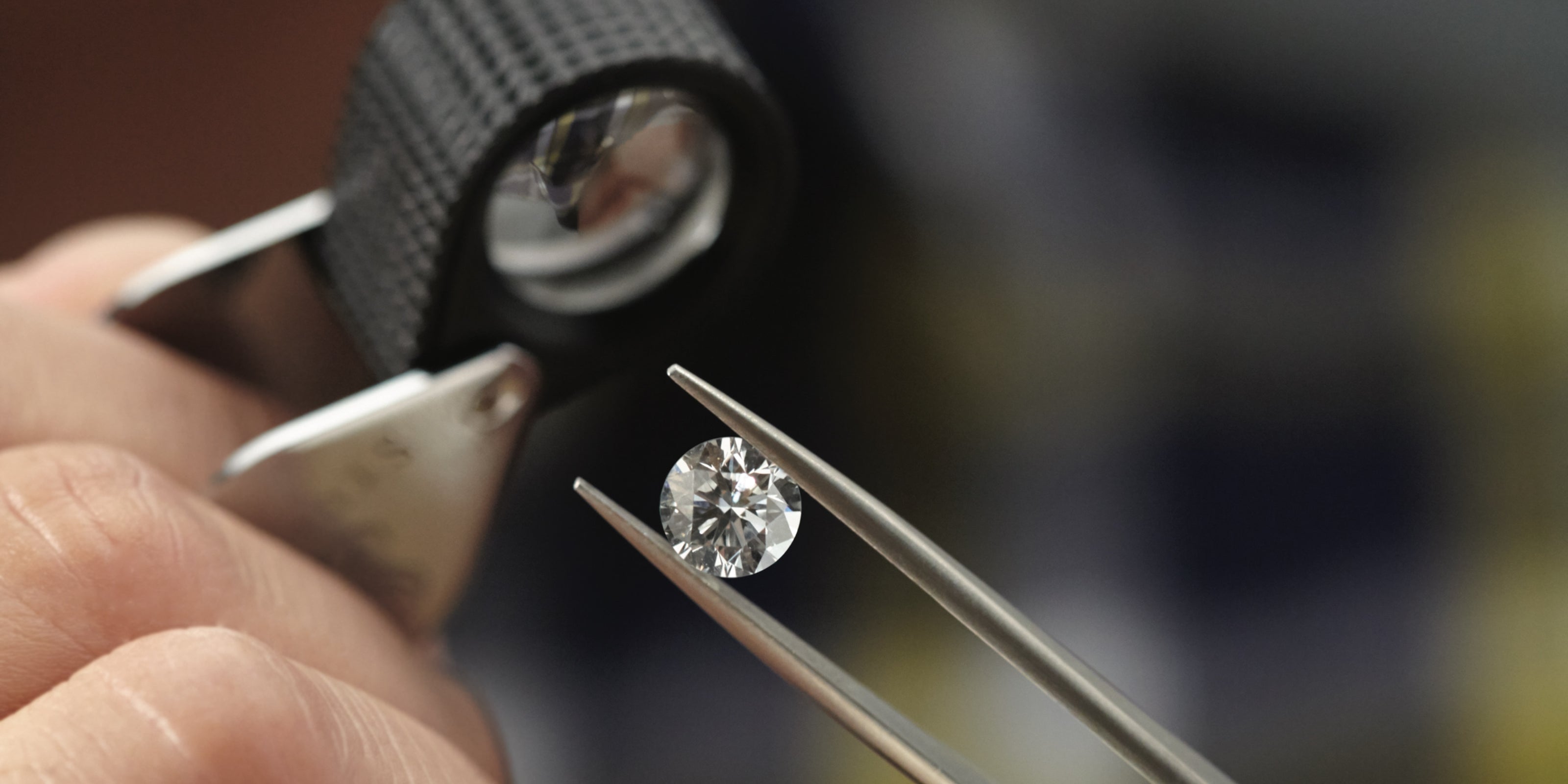 Diamond being held by tweezers with a loupe in close-up