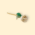 Gold and green rose-shaped earring on a beige background