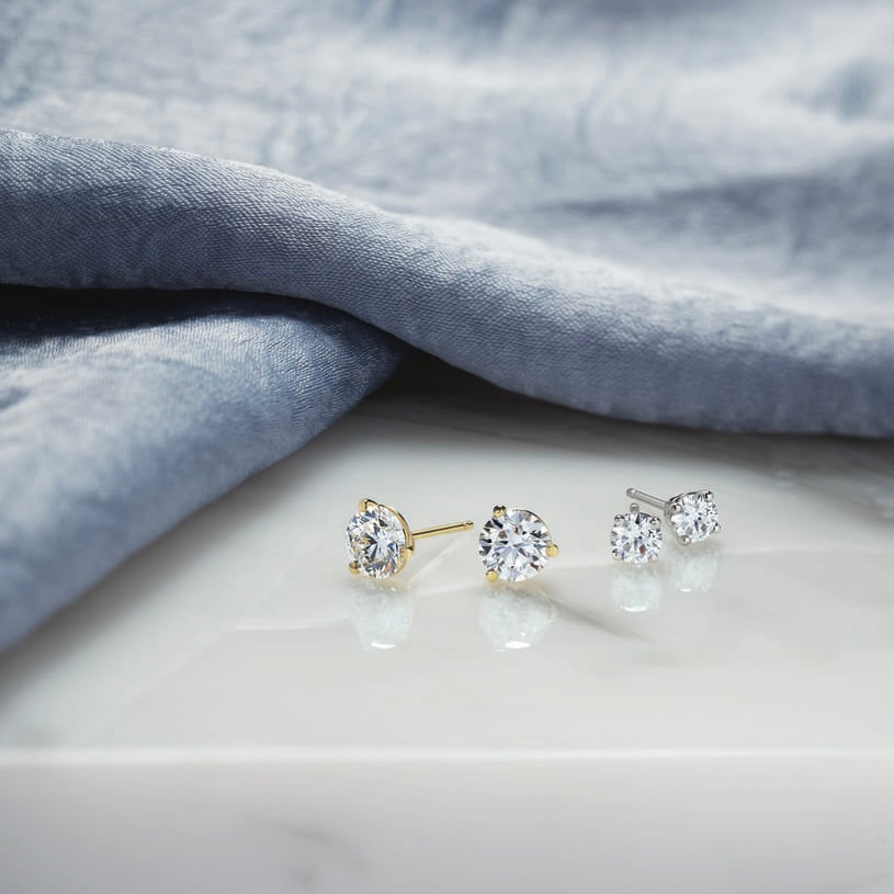 Pair of diamond stud earrings on a light gray fabric background