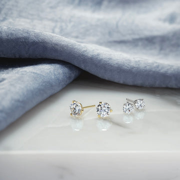 Pair of diamond stud earrings on a light gray fabric background
