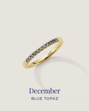Gold ring with blue gemstones on a light gray background, labeled 'December Blue Topaz'.
